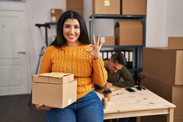 Poster - Young woman and man working at small business ecommerce doing ok sign with fingers, smiling friendly gesturing excellent symbol