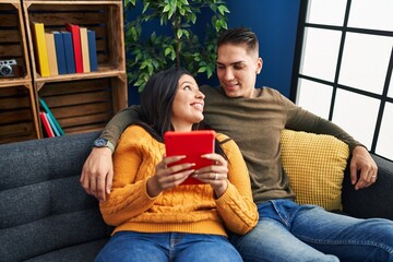 Canvas Print - Man and woman couple hugging each other using touchpad at home