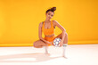 Attractive female brunette girl in fashionable sportswear and stockings posing with football ball , looking at camera, waiting for the soccer competition, championship.