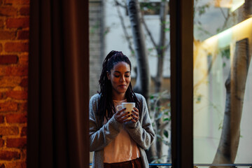 Young adult woman drinks coffee at home