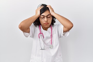 Wall Mural - Young hispanic doctor woman wearing stethoscope over isolated background suffering from headache desperate and stressed because pain and migraine. hands on head.