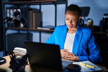 Canvas Print - Beautiful african american woman working at the office at night with hand on stomach because indigestion, painful illness feeling unwell. ache concept.