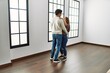 Young hispanic couple smiling happy dancing at empty new home.