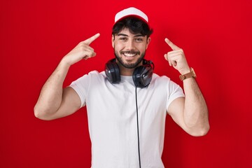 Sticker - Hispanic man with beard wearing gamer hat and headphones smiling pointing to head with both hands finger, great idea or thought, good memory