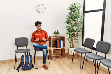 Canvas Print - Young hispanic man reading book at waiting room