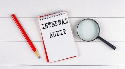 Poster - INTERNAL AUDIT text on notebook on white wooden background , business concept