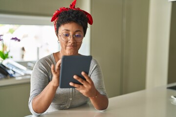 Poster - African american woman using touchpad sitting on table at home