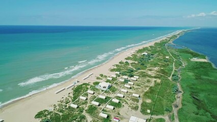 Wall Mural - Aerial over the long sandy spit with a beach and azure water on a sunny summer day. Waves crashing to the shore. Relaxing calm atmosphere. Panoramic seascape
