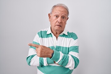 Wall Mural - Senior man with grey hair standing over white background pointing aside worried and nervous with forefinger, concerned and surprised expression