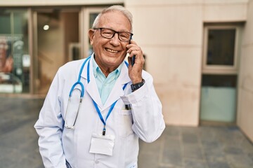 Wall Mural - Senior man wearing doctor uniform talking on the smartphone at street