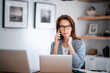 © sepy - Serious faced woman having a call and using laptop while working from home