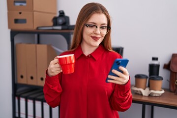 Wall Mural - Young redhead woman business worker using smartphone drinking coffee at office