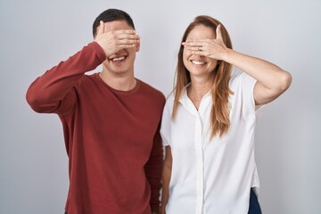 Canvas Print - Mother and son standing together over isolated background smiling and laughing with hand on face covering eyes for surprise. blind concept.