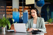© ABCreative - Serious buisness woman at caffe working online wearing modern new headphones and sitting in front of computer. Working process concept.