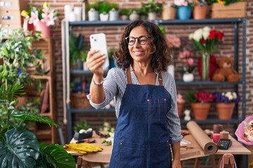 Wall Mural - Middle age woman florist smiling confident having video call at flower shop