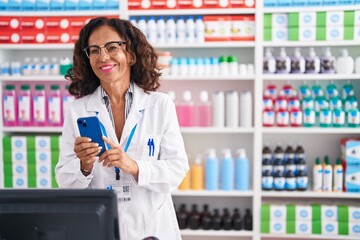 Sticker - Middle age woman pharmacist using smartphone working at pharmacy