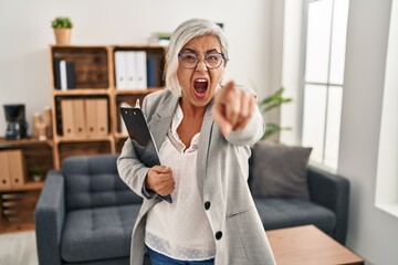 Poster - Middle age woman with grey hair at consultation office pointing displeased and frustrated to the camera, angry and furious with you