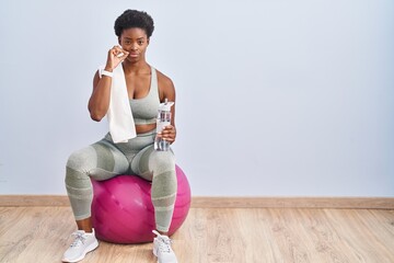 Sticker - African american woman wearing sportswear sitting on pilates ball mouth and lips shut as zip with fingers. secret and silent, taboo talking