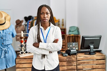 Canvas Print - Black woman with braids working as manager at retail boutique skeptic and nervous, disapproving expression on face with crossed arms. negative person.