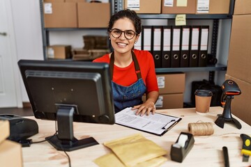 Poster - Young latin woman ecommerce business worker writing on clipboard at office