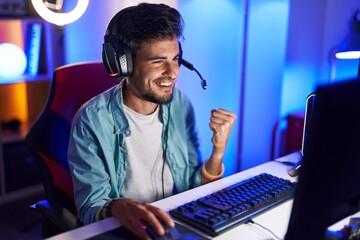 Poster - Young hispanic man streamer playing video game with winner expression at gaming room