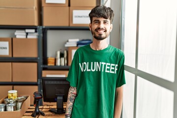 Sticker - Young hispanic man wearing volunteer uniform standing at charity center.