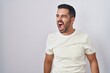 © Krakenimages.com - Hispanic man with beard standing over isolated background angry and mad screaming frustrated and furious, shouting with anger. rage and aggressive concept.