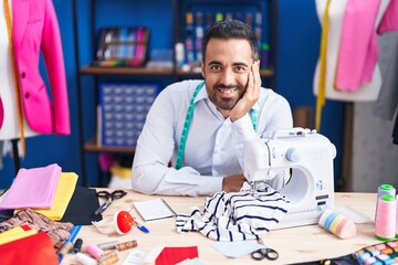 Sticker - Young hispanic man tailor smiling confident sitting on table at sewing studio