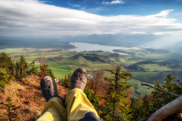 Wall Mural - Legs of hiker with hiking boots on top of the hill with beautiful landscape under