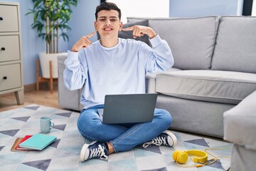 Poster - Non binary person studying using computer laptop sitting on the floor smiling cheerful showing and pointing with fingers teeth and mouth. dental health concept.