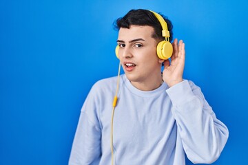 Poster - Non binary person listening to music using headphones smiling with hand over ear listening an hearing to rumor or gossip. deafness concept.