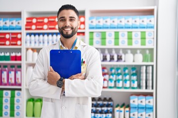 Sticker - Young arab man pharmacist smiling confident holding clipboard at pharmacy