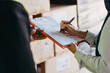 © Jacob Lund - Warehouse manager signing a bill of lading on a clipboard