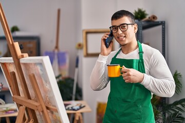 Sticker - Young man artist talking on the smartphone drinking coffee at art studio