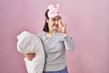 Wall Mural - Woman with down syndrome wearing sleeping mask hugging pillow waiving saying hello happy and smiling, friendly welcome gesture