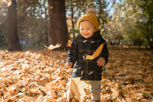 Smiling Boy Wearing Knit Hat Playing In Park In Autumn