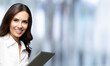 © vgstudio - Happy smiling beautiful young brunette businesswoman using no-name tablet pc, against blurred office background, with copy space area for text. Success in business concept.