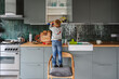 © Westend61 - Boy searching in kitchen cabinet standing on chair at home