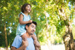 Happy Asian father with daughter on his neck. Happy man enjoying rest in park and little girl sitting on his shoulders looking aside. Family summer activity, rest and happy moments concept