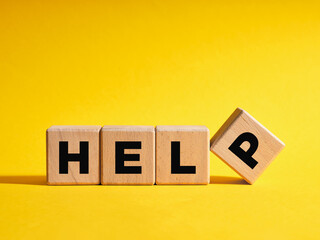 Wall Mural - The word Help on wooden cubes with yellow background. Support, assistance or aid concept.