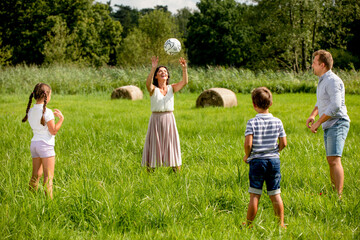 Parents with children playing ball in the park on green grass