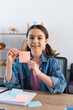 © LIGHTFIELD STUDIOS - cheerful girl showing empty sticky note and looking at camera at home.