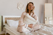 © mary_markevich - pretty smiling woman relaxing at home on bed in morning in pajamas