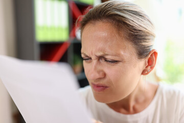 Focused woman trying read papers, squinting to see more clearly