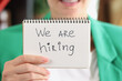 Woman hand holding paper with lettering we are hiring