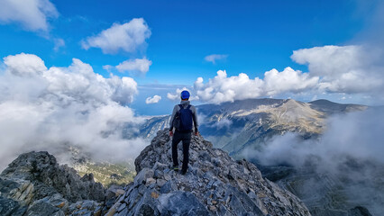 rear view of man with climbing helmet on cloud covered mountain summit of mytikas mount olympus, mt 