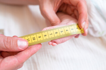 The baby's foot is measured with a measuring tape. choosing the size for shoes