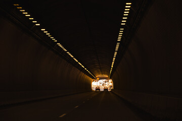 View of interstate highway tunnel through mountains in winter; exit in background