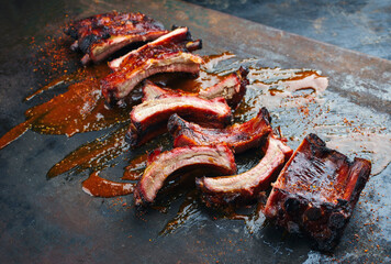 Wall Mural - Barbecue pork spare loin ribs St Louis cut with hot honey chili sauce served as close-up on a rustic black board