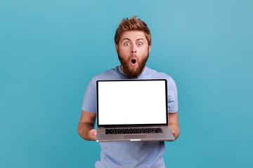 Wall Mural - portrait of bearded man holding and showing laptop with blank empty display, place for your advertis